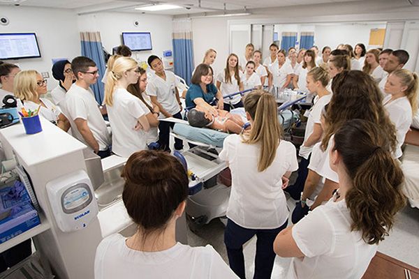 Large group of students observe instructor demonstrating on a manikin