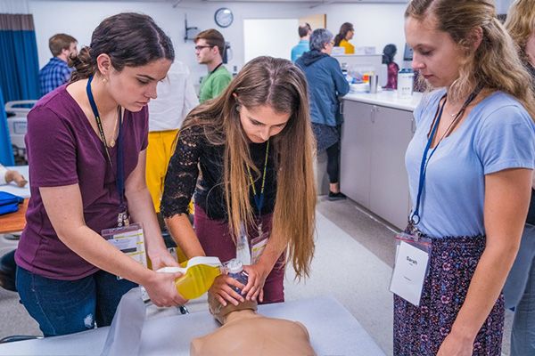Instructor supervises two students practicing on a manikin